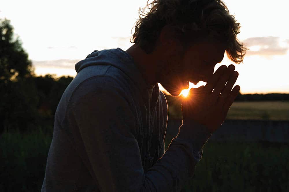 Silhouette of man praying at sunset